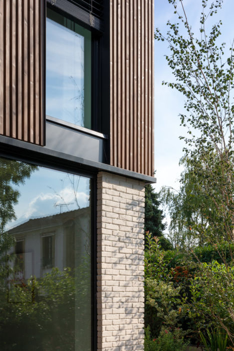 Détail façade, vitrage, brique blanche, bois et menuiseries en métal noir