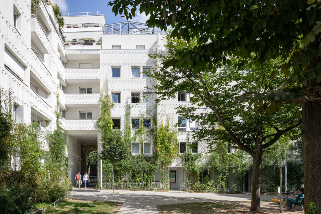 Frederic Bernard Architecture | Square de la Salamandre | Paris 2 personnes passent sous le porche et pénètrent dans le jardin