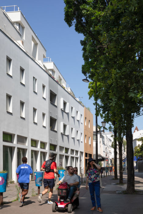 Groupe de personnes le long de la façade sur rue